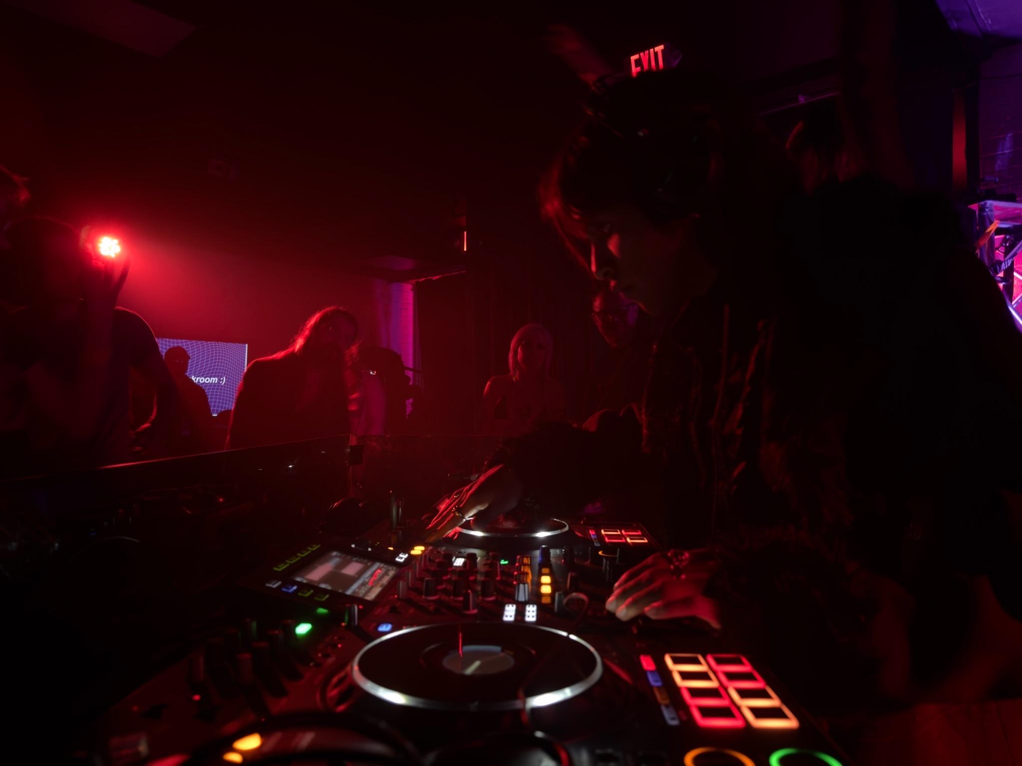 Xinstar performing behind the decks in red club lighting